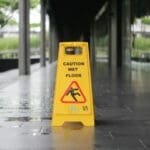 yellow Caution wet floor signage on wet pavement